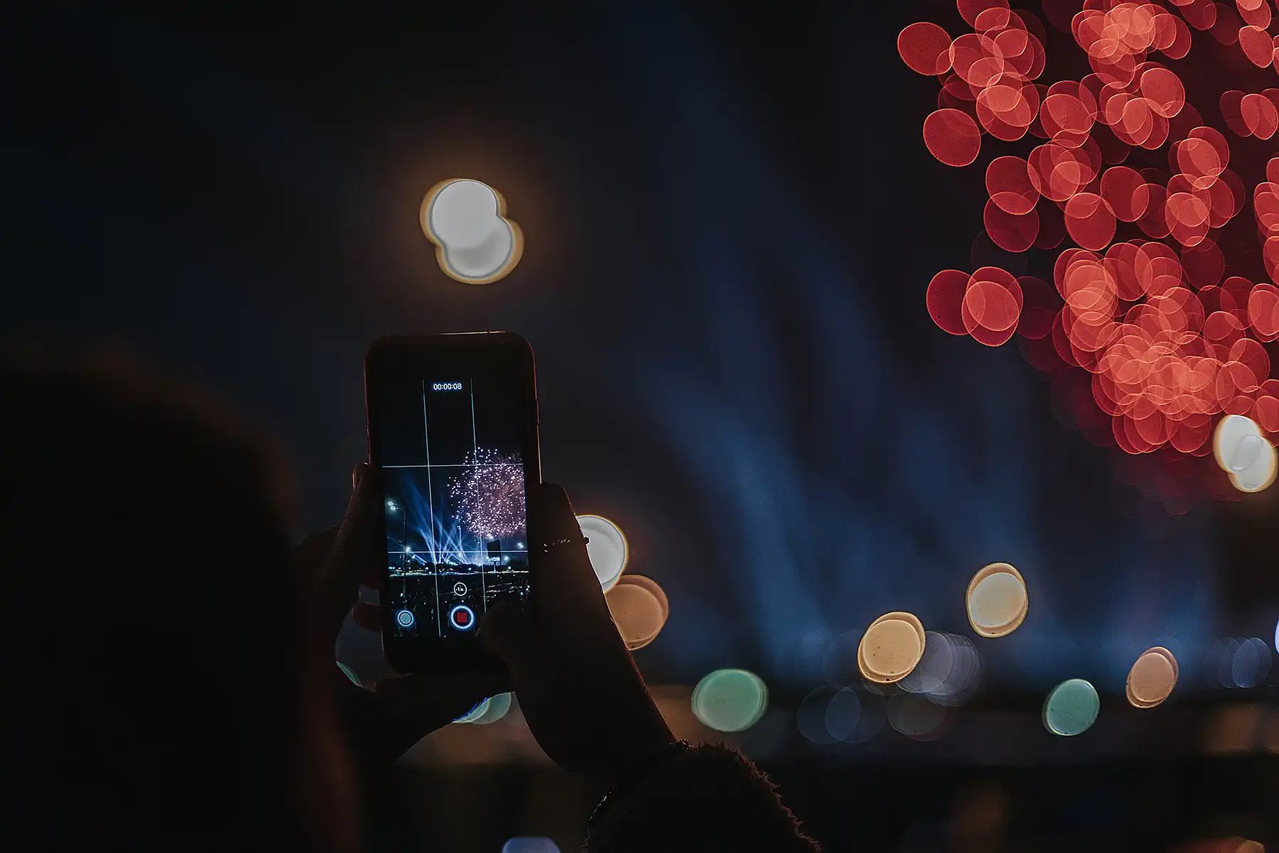 Woman taking a photo of fireworks with her iPhone