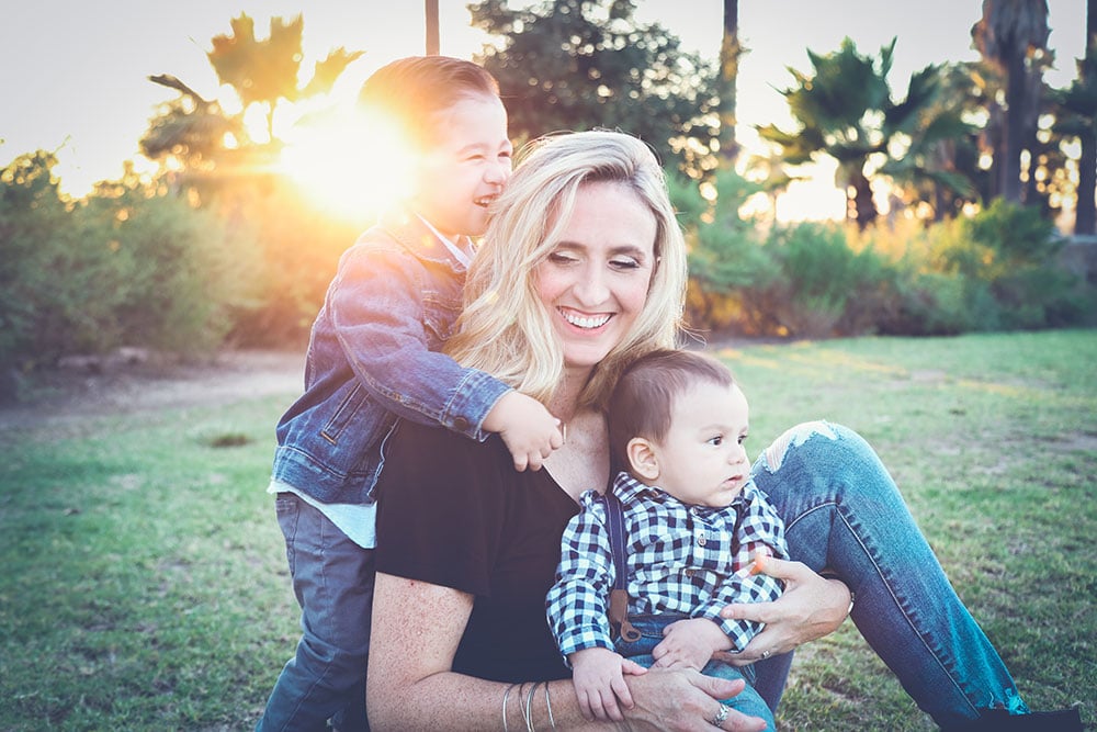 A mother taking a picture with her two kids in a grassy field | Motif