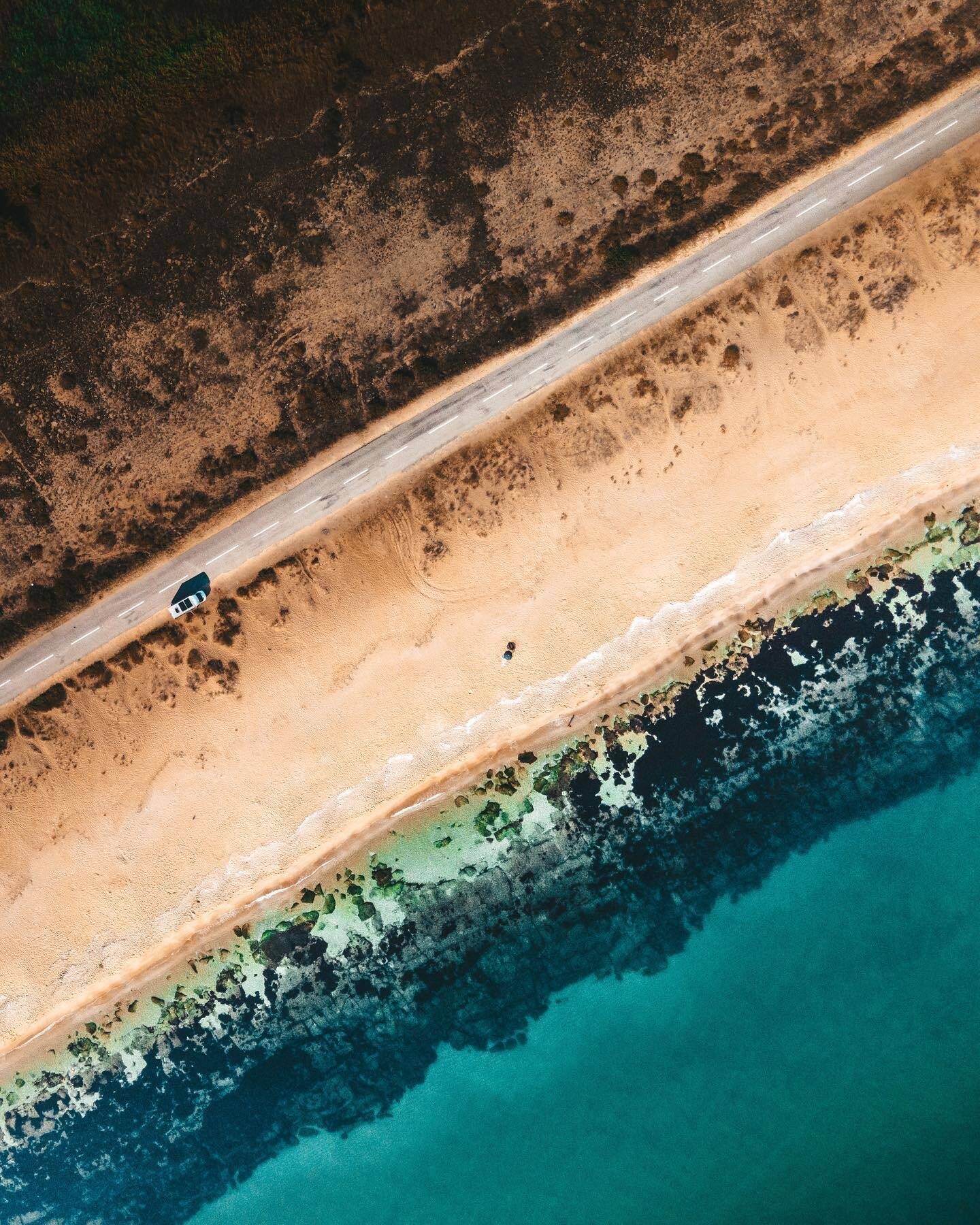 drone birds eye view of car driving along the beach