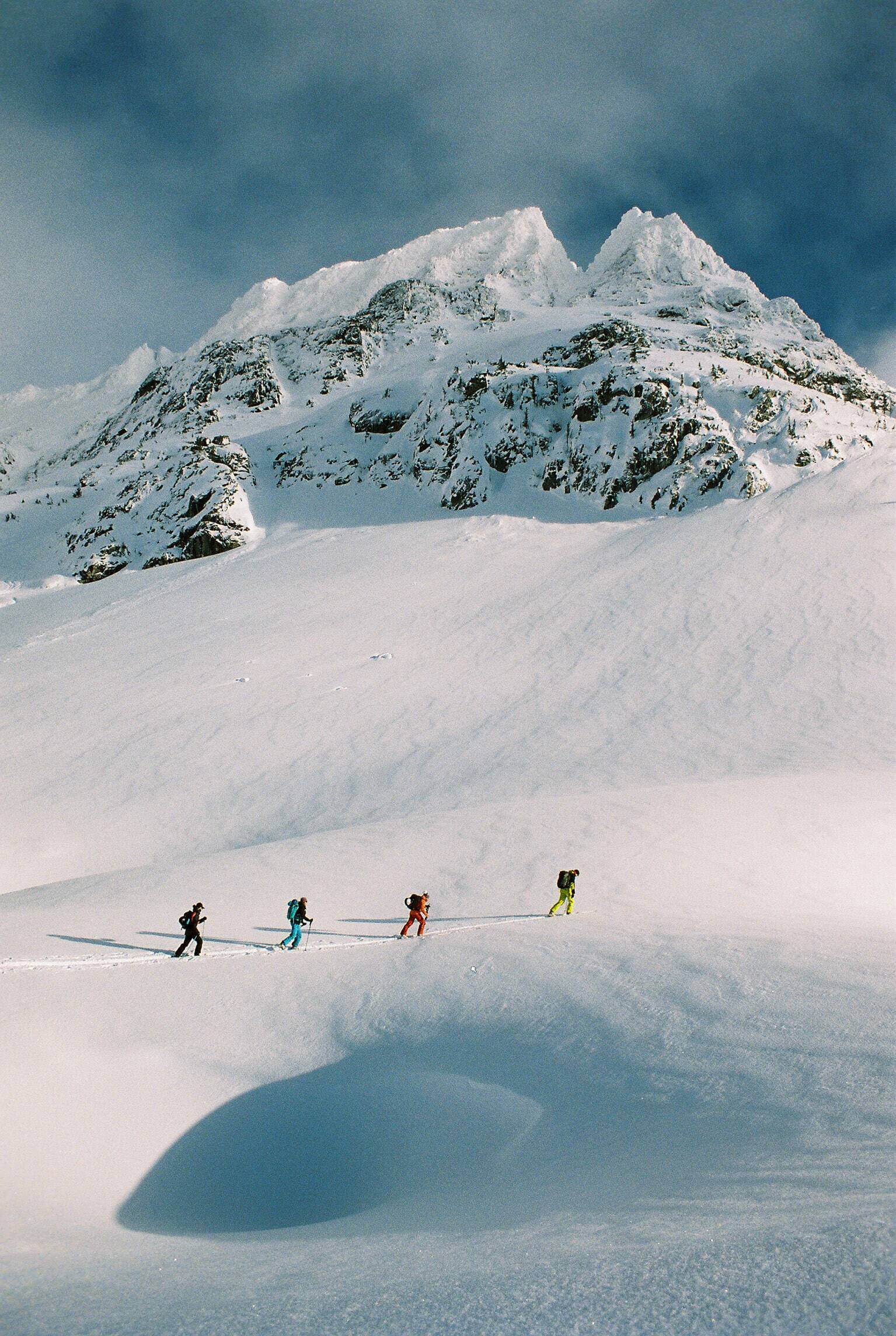 4 hikers walking across snowy landscape