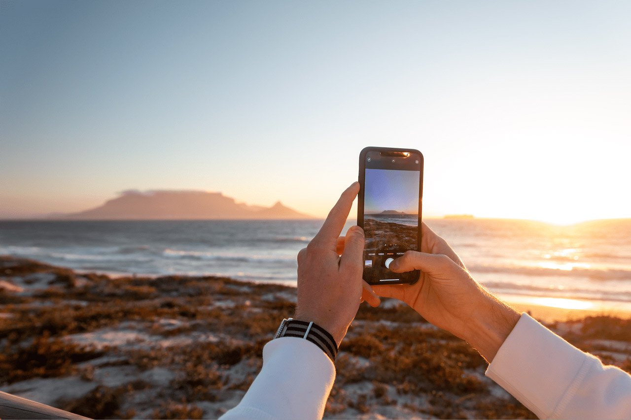 man taking photo of sunset with iphone