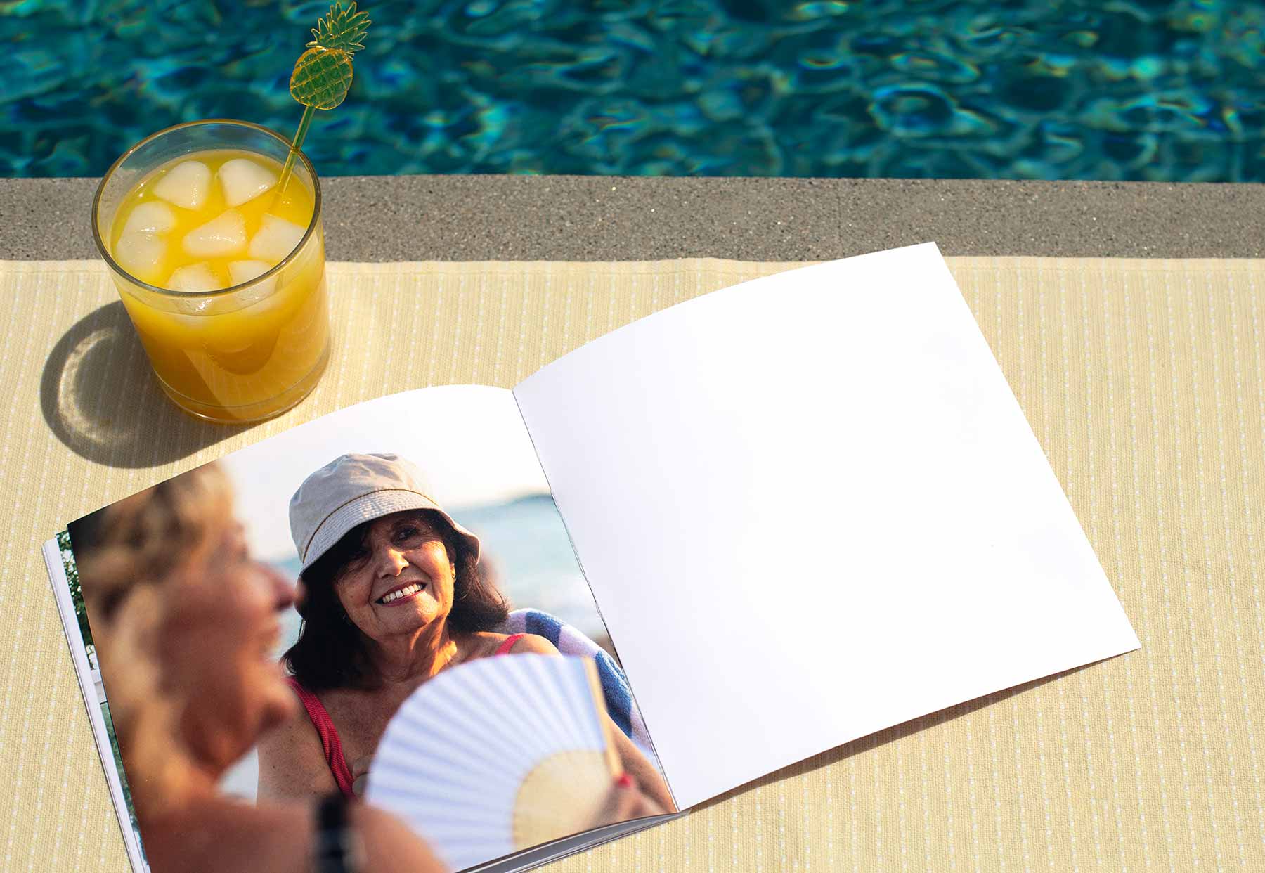 Softcover photo book by a pool with a summer drink