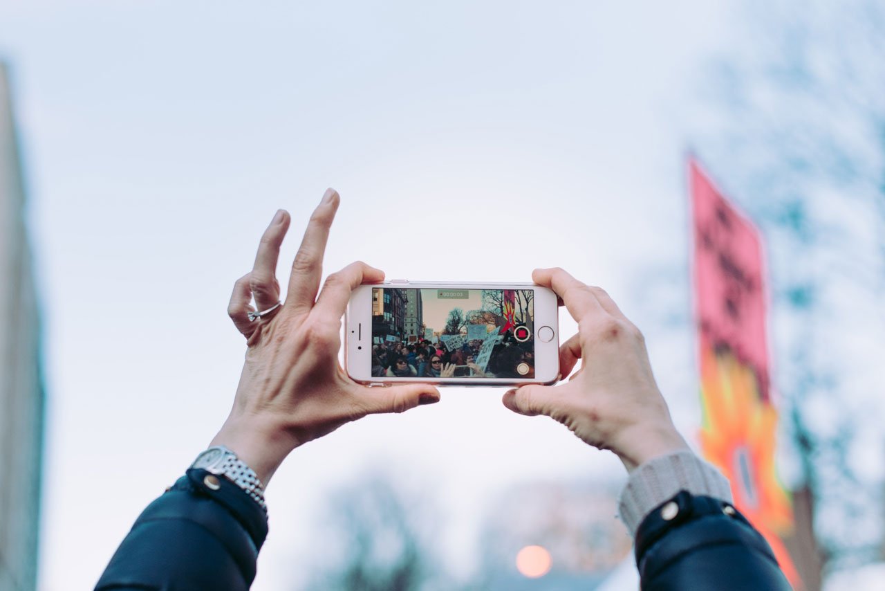 Woman holding iPhone horizontally to take a landscape oriented photo.