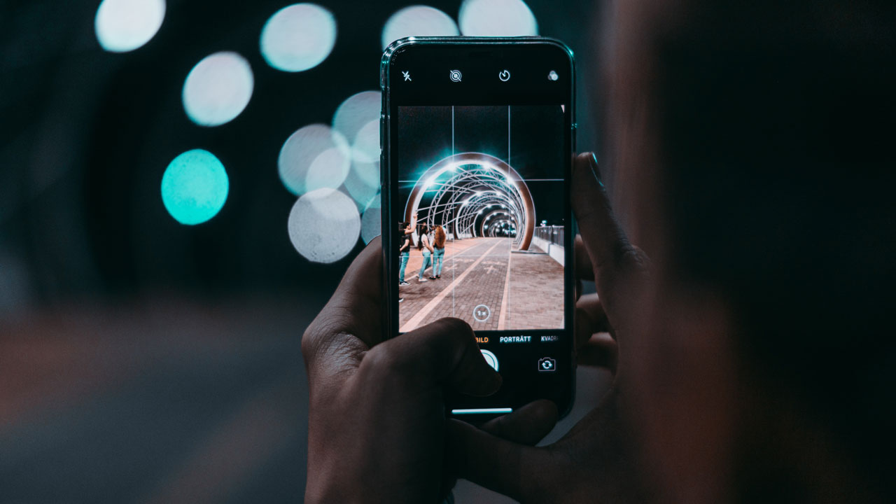 Person taking a photo with an iPhone at night.