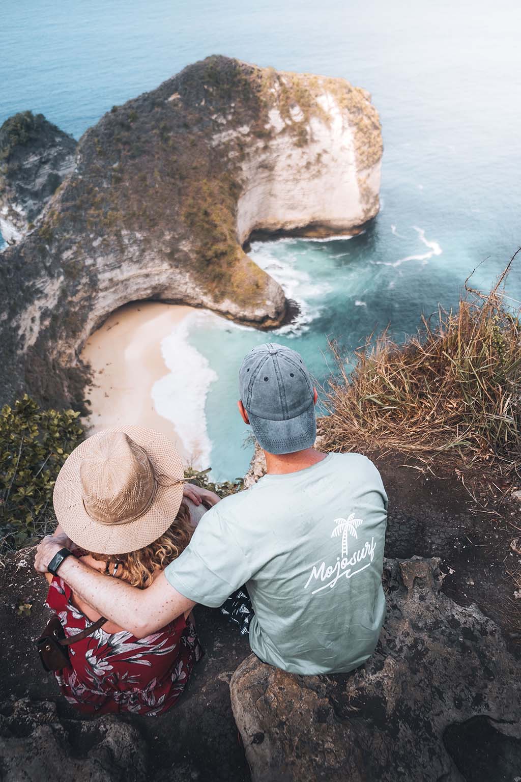 Couple sitting on rocks overlooking beach in Bali