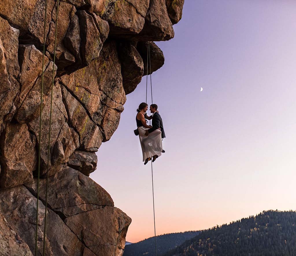 couple suspended in midair holding each other at sunset